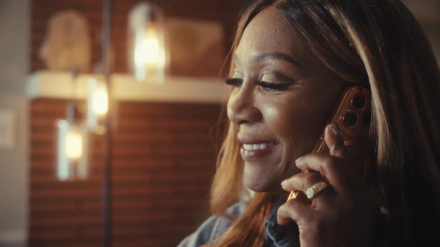 Side profile close-up of a professional woman smiling during a phone call in her modern home office