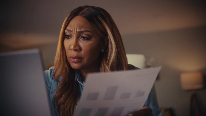 Stressed businesswoman analyzing charts on paper and a laptop computer while working from home at night