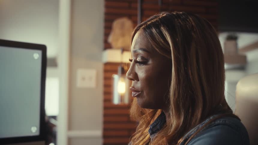 Close-up profile of a woman engaged in a conversation while looking at a computer monitor with a green screen