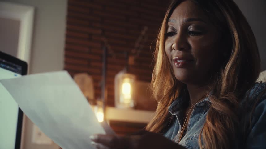 Close-up of a woman working late from her home office, her expression becoming worried as she reviews financial reports