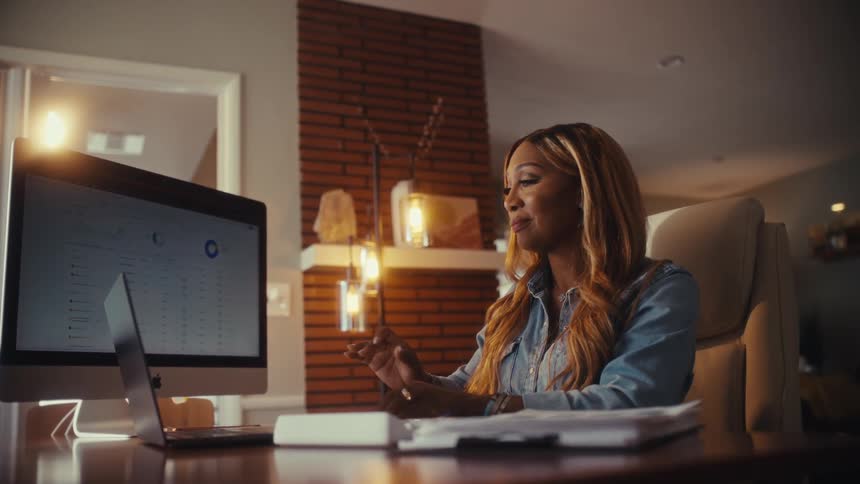 A successful entrepreneur smiles with satisfaction while reviewing positive business analytics on her computer in a modern home office