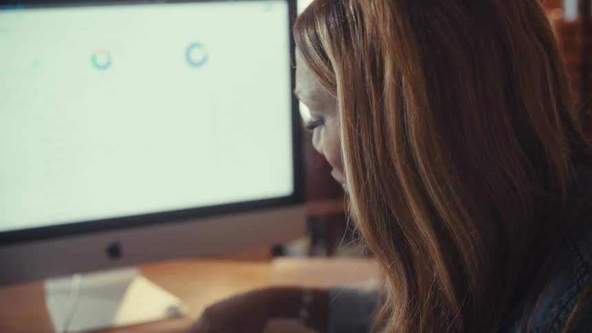 A stressed and worried woman analyzes financial paperwork and reports while working at her desk
