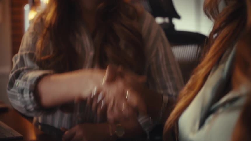 Slow motion close-up of two diverse women shaking hands and smiling after reaching a business agreement in a warmly lit office