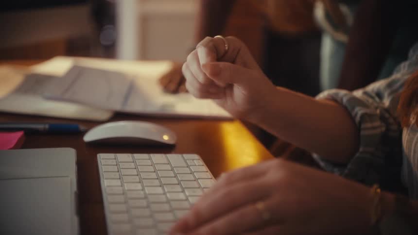 Close up of a businesswoman's hands typing on a keyboard then raising a fist in celebration of success in slow motion