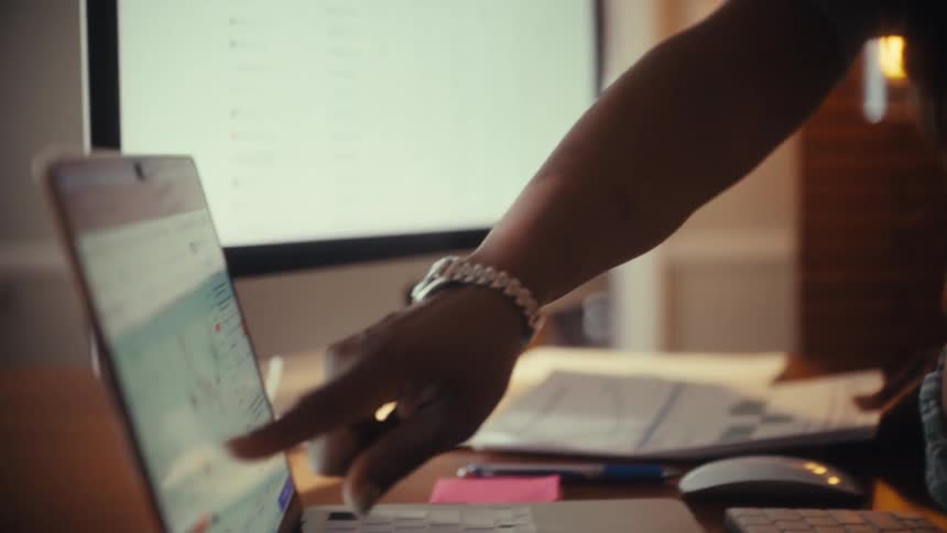 Two diverse female professionals collaborate, analyzing financial charts and data on a laptop in a warmly lit office