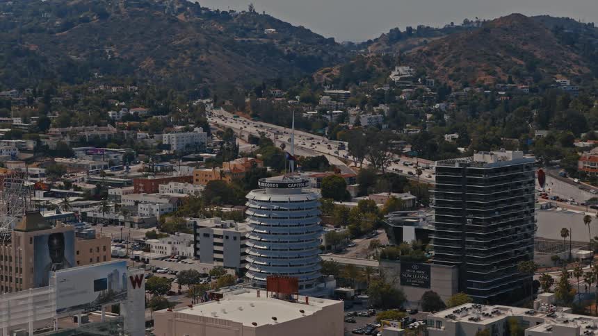 Aerial view of the iconic Capitol Records Building, the bustling Hollywood Freeway, and the Hollywood Hills during the day