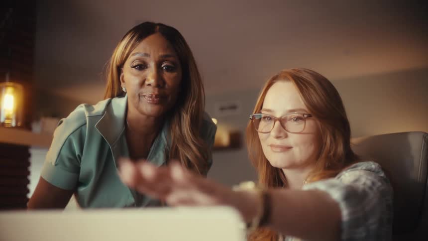 Two diverse businesswomen successfully collaborate on a project and finalize their agreement with a handshake in a modern office