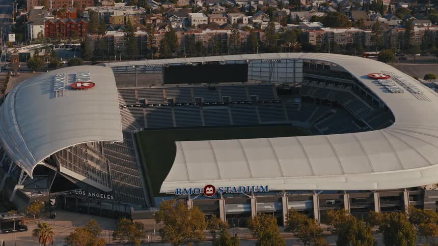 An aerial view slowly orbits the modern and empty BMO Stadium in Los Angeles during a quiet day