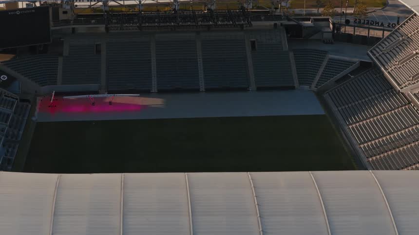 A stunning aerial view captures the vast, empty BMO Stadium in Los Angeles, slowly revealing the grand architecture and a brightly lit stage on the field