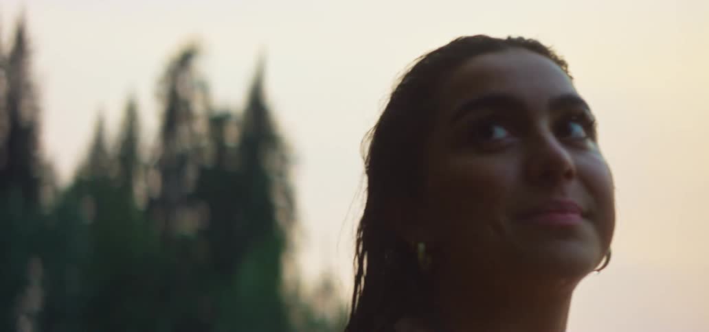 Serene close-up of a young woman with wet hair looking up at the sky while relaxing in the water at dusk