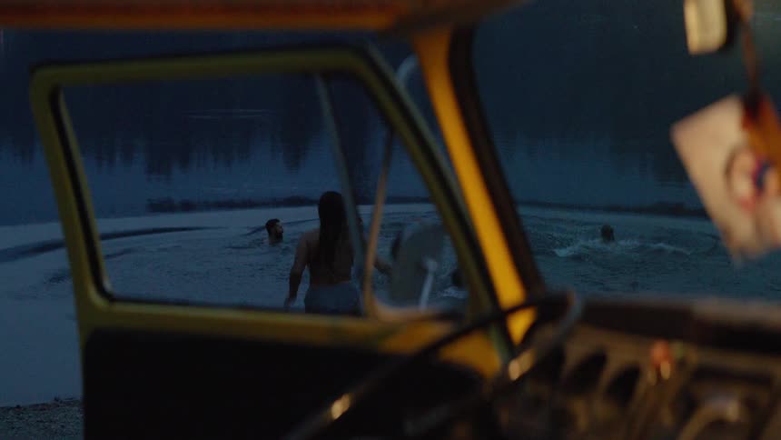 From inside a vintage yellow van, a group of friends runs into a lake for a spontaneous and fun night swim
