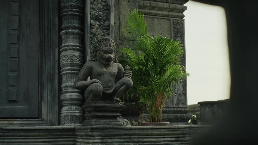 An ancient stone guardian statue with a fearsome expression stands watch at the entrance to a temple