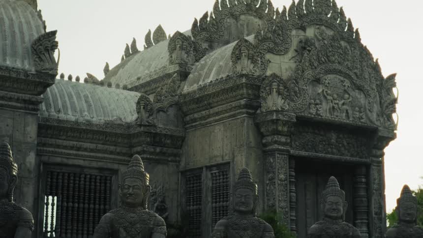 A close-up tilting shot reveals the intricate stone carvings and architecture of an ancient Southeast Asian temple