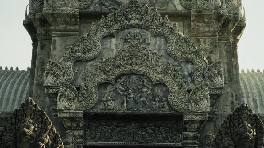 A slow tilt reveals the intricate stone carvings on an ancient Southeast Asian temple entrance