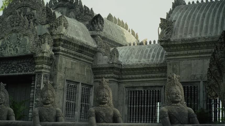 A majestic stone temple with intricate carvings, guardian statues, and multi-headed Naga serpents stands under a clear sky