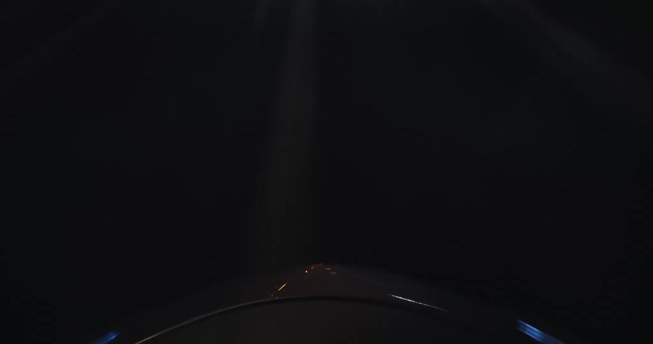 Dynamic time-lapse from the hood of a car racing down a highway at night, showing blurred lights and streaking road lines