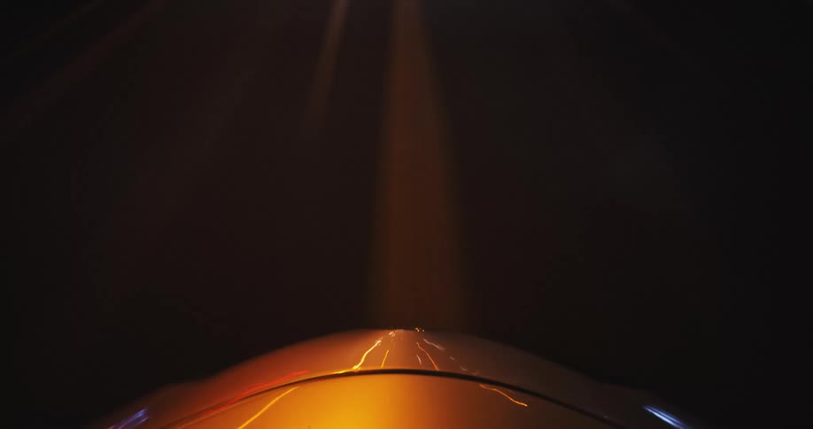 A hypnotic long-exposure time-lapse shot from the hood of a car as it speeds through a brightly illuminated tunnel at night