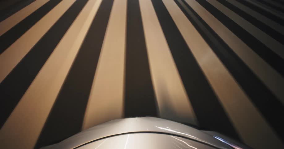 A fast-paced time-lapse from the hood of a car captures streaks of light while driving through a city tunnel at night