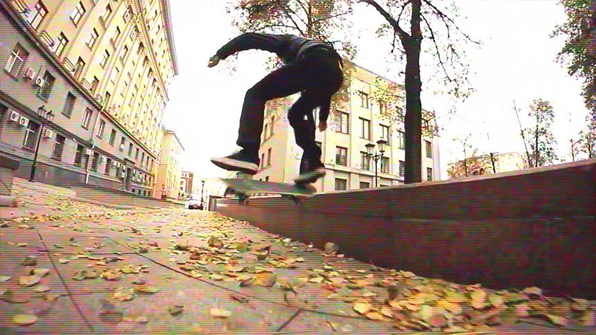A skateboarder in a black hoodie fails a trick on a city ledge but recovers with a smooth slide in slow motion