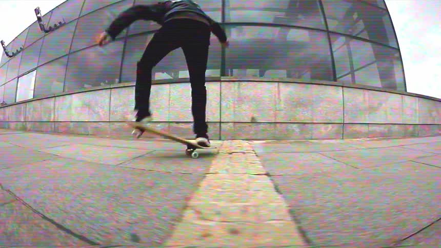 A young man skillfully performs skateboarding tricks in slow motion on a city plaza with a retro VHS filter