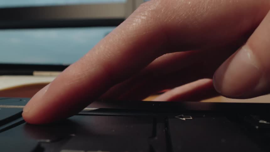 A dynamic macro shot captures fingers rapidly typing on a laptop keyboard before resting on a key