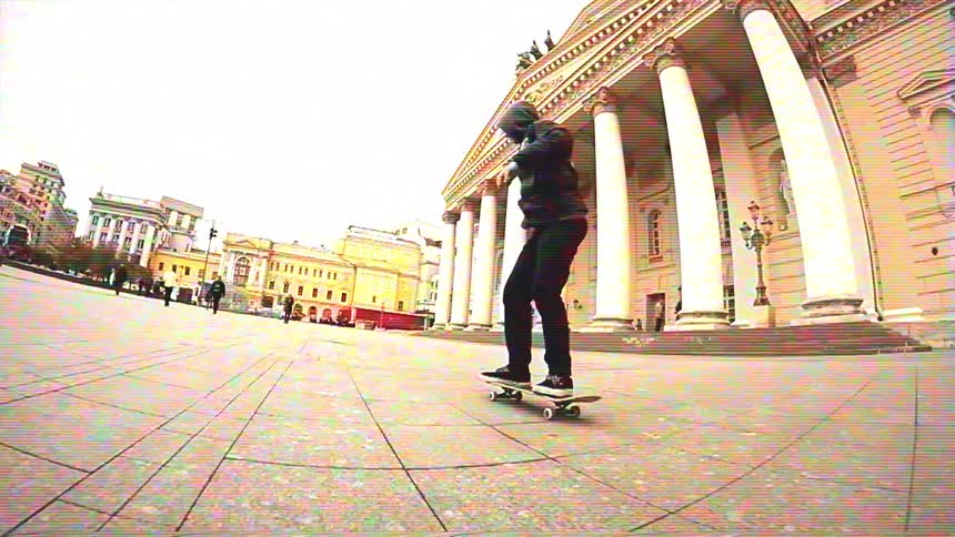 A hooded skateboarder executes a stylish trick in slow motion across a grand city plaza, filmed with a fisheye lens and a vintage VHS aesthetic