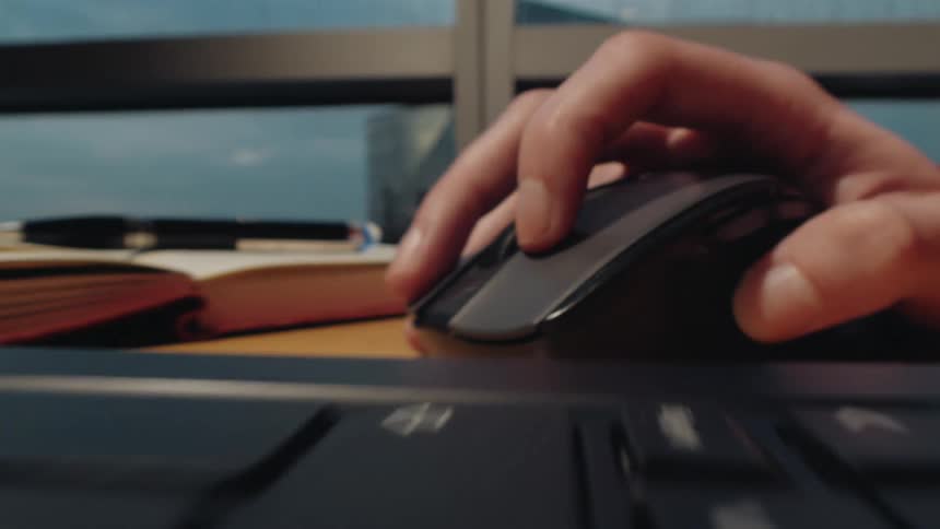 A dynamic macro shot slides from fingers typing on a laptop keyboard to a hand scrolling with a wireless mouse at a modern desk