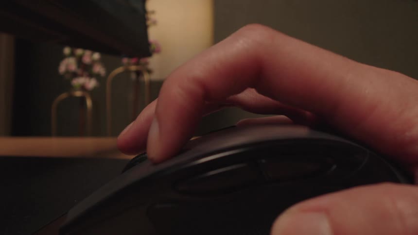 Close-up of a person's hand using a computer mouse, clicking and scrolling while working at a desk