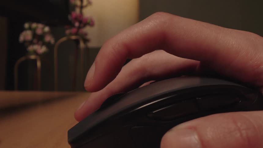 A close-up of an impatient hand tapping its finger on a computer mouse while waiting