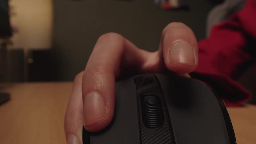 A close-up, front-facing view of a person's hand repeatedly clicking and scrolling on a wireless computer mouse