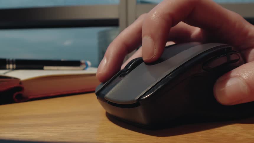 A dynamic close-up shot moves from a person typing on a laptop keyboard to their hand using a wireless mouse on a desk