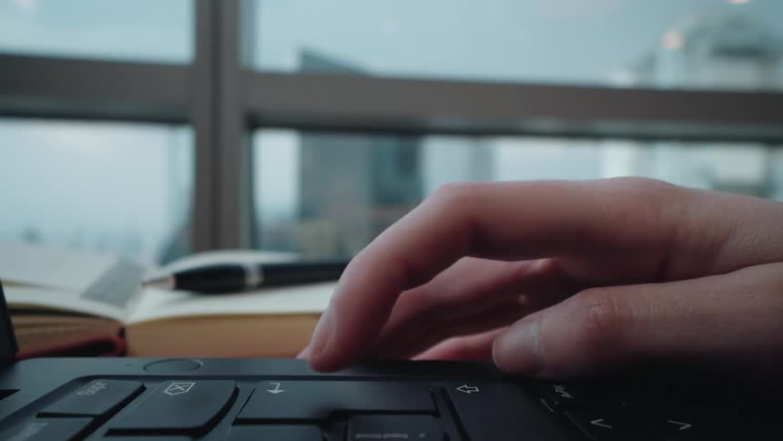 Cinemagraph loop of a hand scrolling and tapping on a laptop touchpad in a modern office with a city view