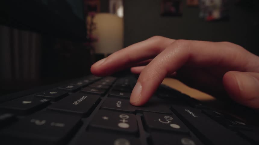 A dramatic slow push-in, low-angle shot captures a person's finger decisively pressing the enter key on a black keyboard