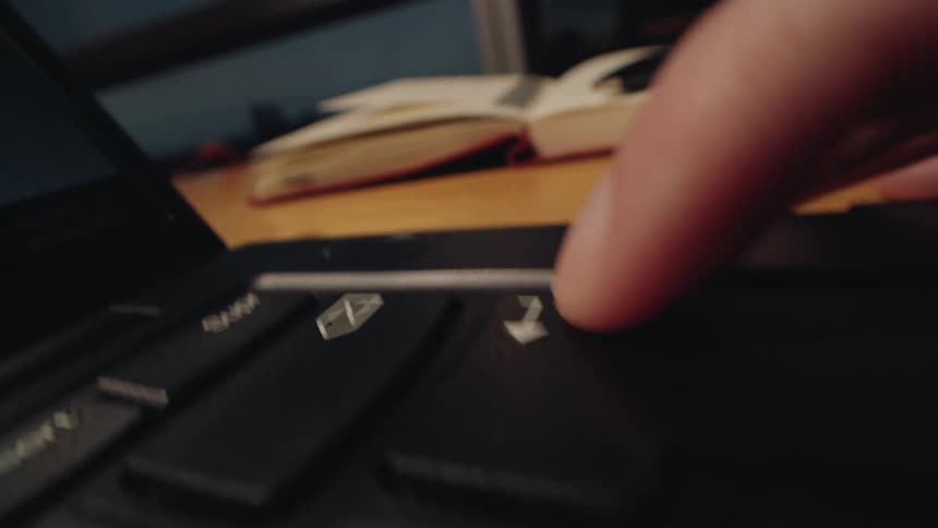 Extreme close-up footage shows a finger repeatedly hitting the enter key on a laptop