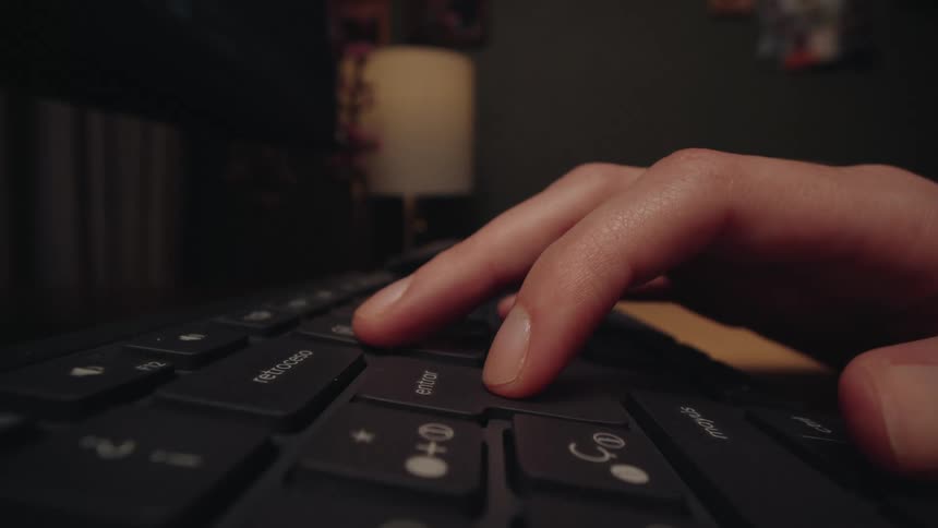 An extreme close-up shot shows a person's fingers typing on a keyboard, then pausing to repeatedly press the enter key