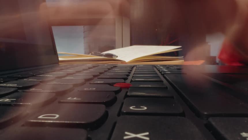 A time-lapse from a low angle shows hands typing frantically on a laptop keyboard, symbolizing deadlines and productivity