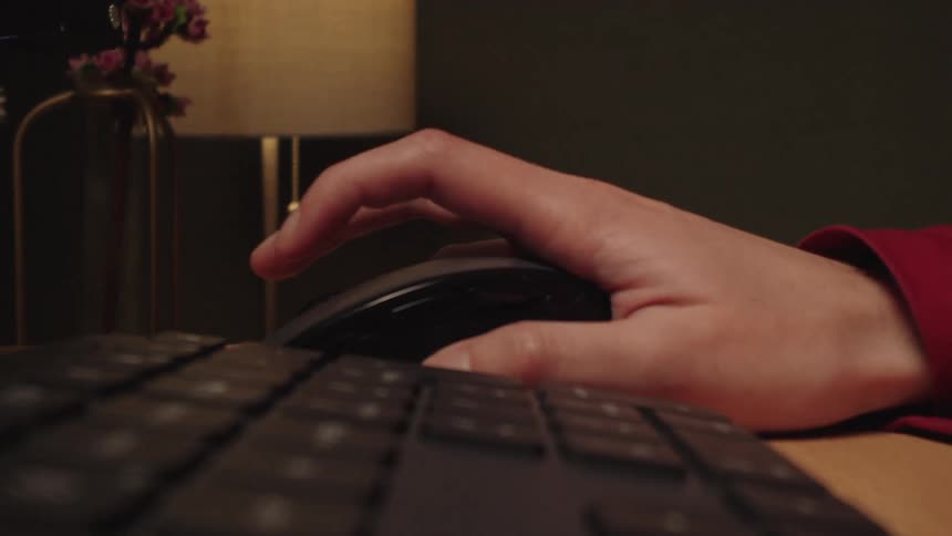 Close-up of a hand typing on a keyboard and then clicking and scrolling on a computer mouse at a desk