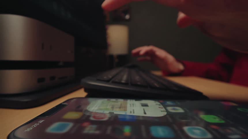 An extreme close-up shot pulls back from fingers typing on a keyboard to a person browsing an online shopping app on their smartphone