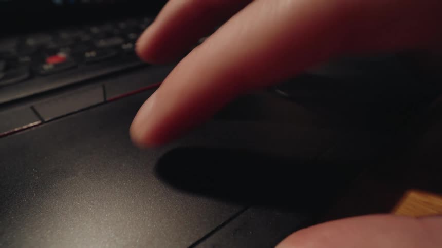 Extreme close-up of fingers scrolling on a laptop trackpad and then typing on the keyboard