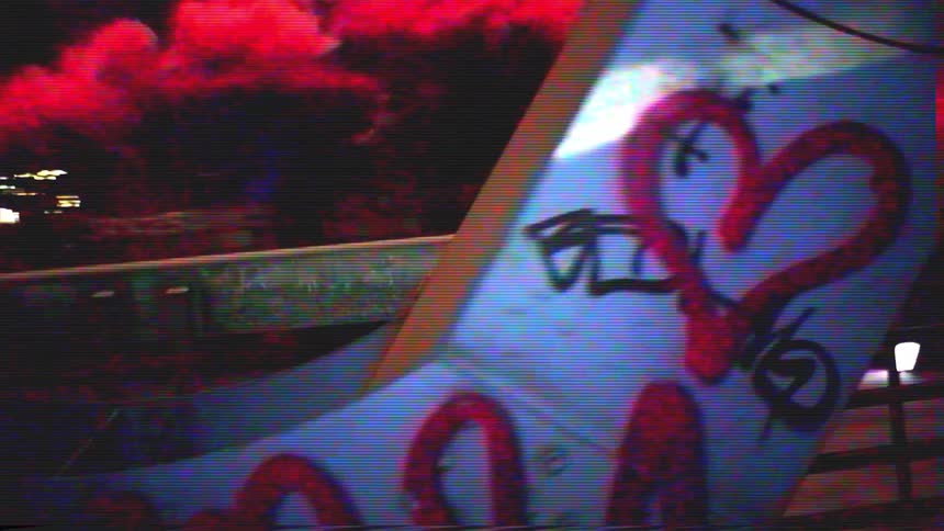 Gritty VHS footage captures a rebellious night scene with red smoke, fireworks, and urban graffiti
