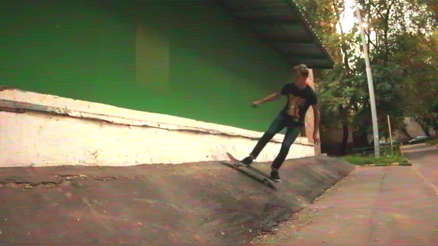 A skateboarder performs a stylish trick on an urban ramp in slow motion, captured with a retro VHS effect