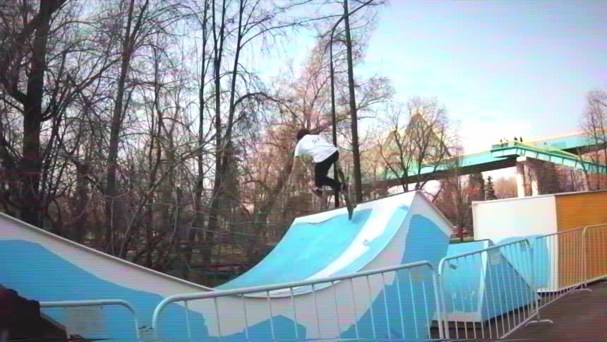 A skateboarder drops into a blue mini ramp and performs tricks in slow motion, shot in a vintage VHS style