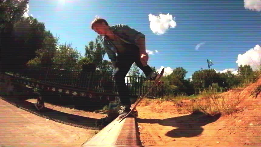 A young skateboarder drops into a concrete ditch, performing a trick in slow motion with a vintage video effect