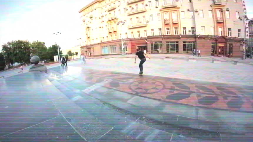 Slow motion fisheye shot of a young man performing a jump trick on his skateboard in a city square