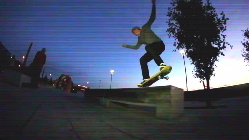 A skateboarder grinds a city ledge in super slow motion against a beautiful twilight sky