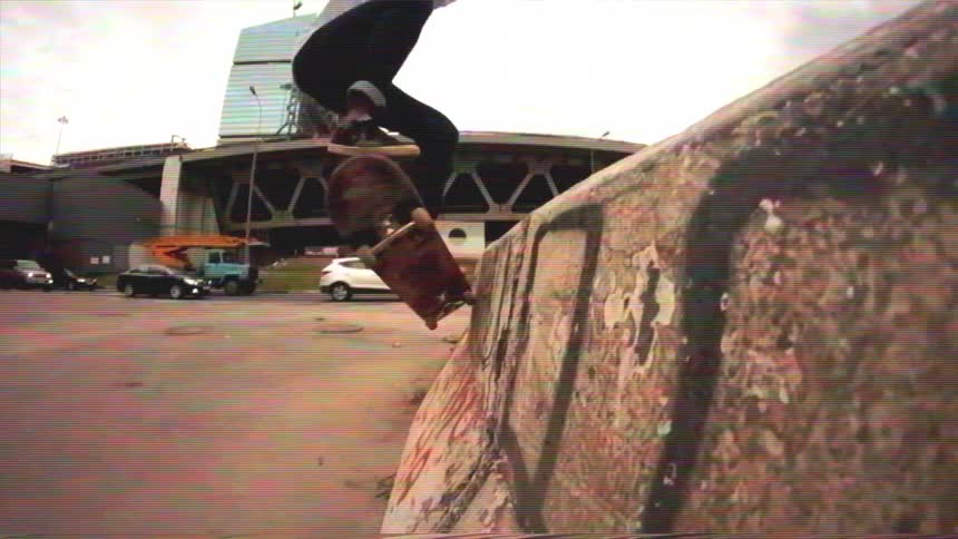 Lo-fi, slow motion footage of a skateboarder doing a trick on a concrete ramp in a gritty urban city setting