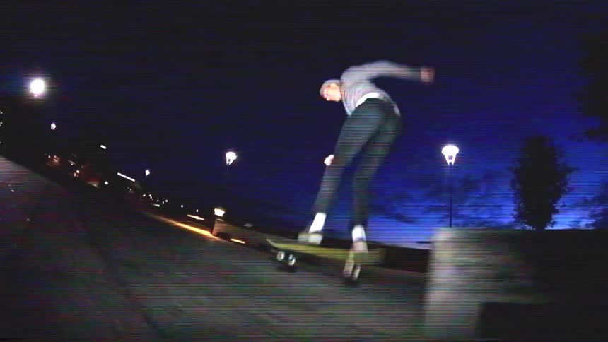 A skateboarder performs a series of tricks in super slow motion at night, with a distinct retro VHS aesthetic