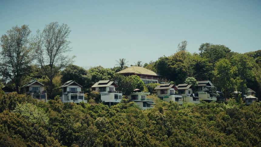 A serene view of luxury villas surrounded by dense tropical foliage on a sunny day