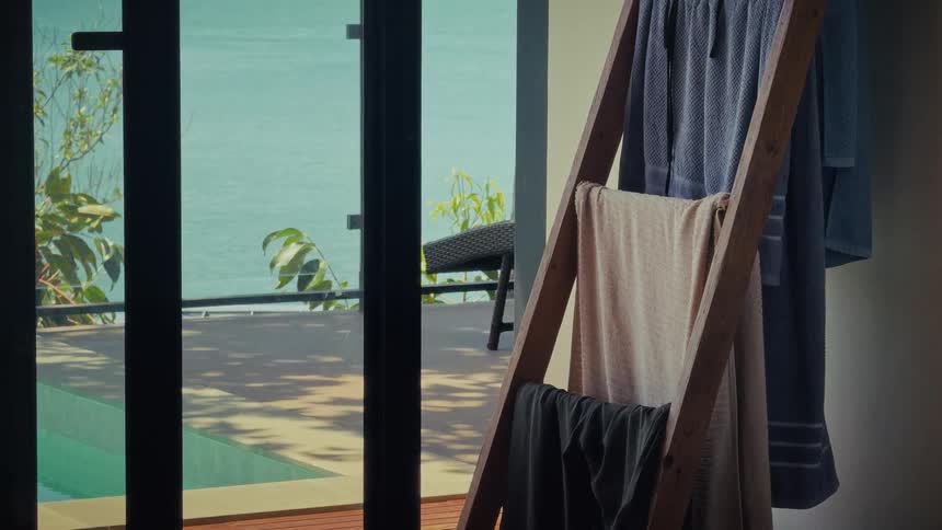 Towels dry on a wooden rack in a luxury hotel room with a private pool overlooking the tranquil ocean
