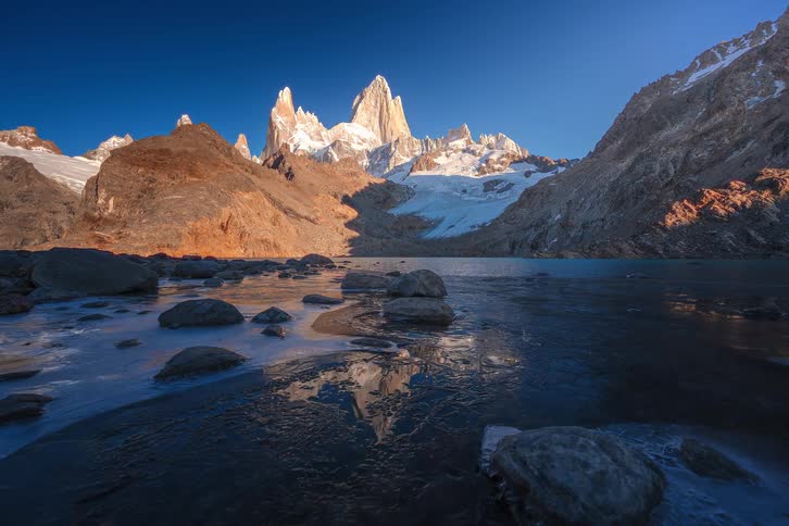 Stunning time-lapse of the sun rising over the iconic Mount Fitz Roy in Patagonia, its golden peaks reflected in the icy waters of an alpine lake